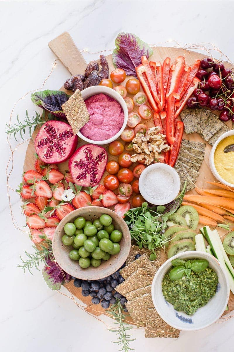 Detail of a vegan platter showing off green olives, red beet dip and contrasting fresh produce