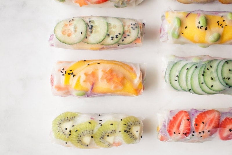 Close up of summer rice paper rolls filled with a rainbow of fruits and vegetables on marble counter