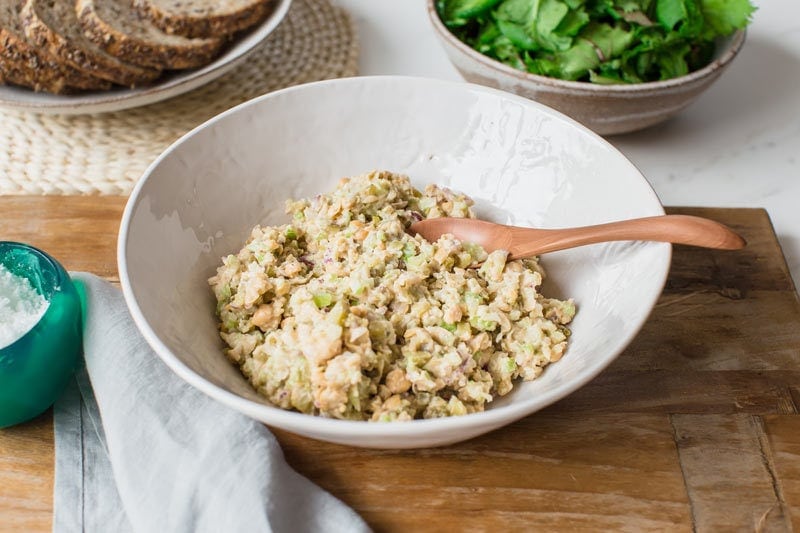 Smashed chickpea filling mixed together in a white bowl ready to spread over sandwiches