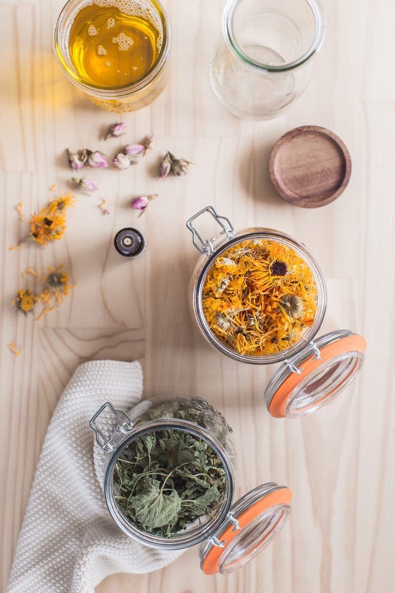 Jars of dried herbs and oils ready for making a DIY body oil