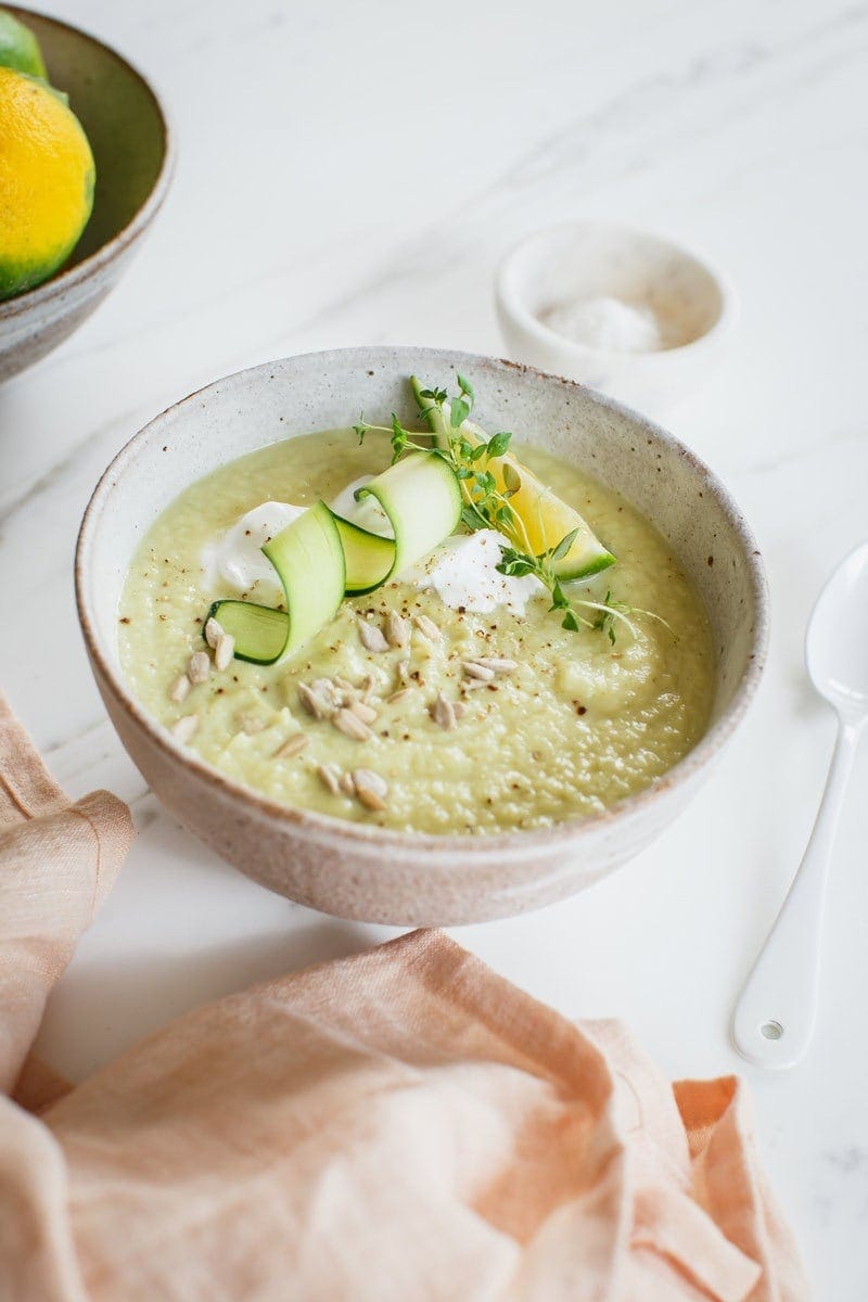 Close up of homemade creamy celeriac soup in a ceramic bowl with a white enamel spoon