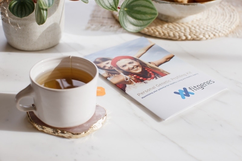 Lifestyle shot of a brochure on the counter with a cup of tea, bowl of fruit and pot plant in background.