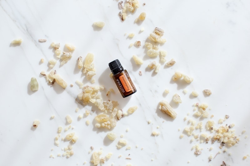 doTERRA frankincense essential oil surrounded by chunks of resin on a marble surface