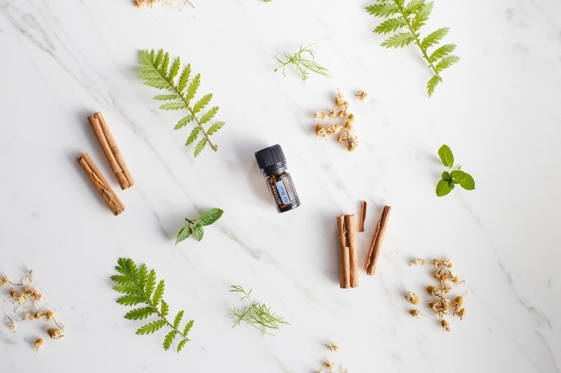 doTERRA IceBlue blend surrounded by fresh aromatic herbs and spices on a marble surface