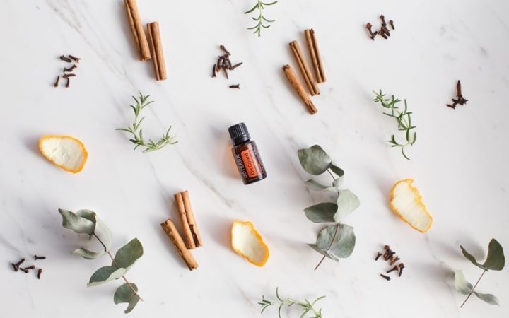 doTERRA OnGuard blend surrounded by fresh aromatic herbs and spices on a marble surface