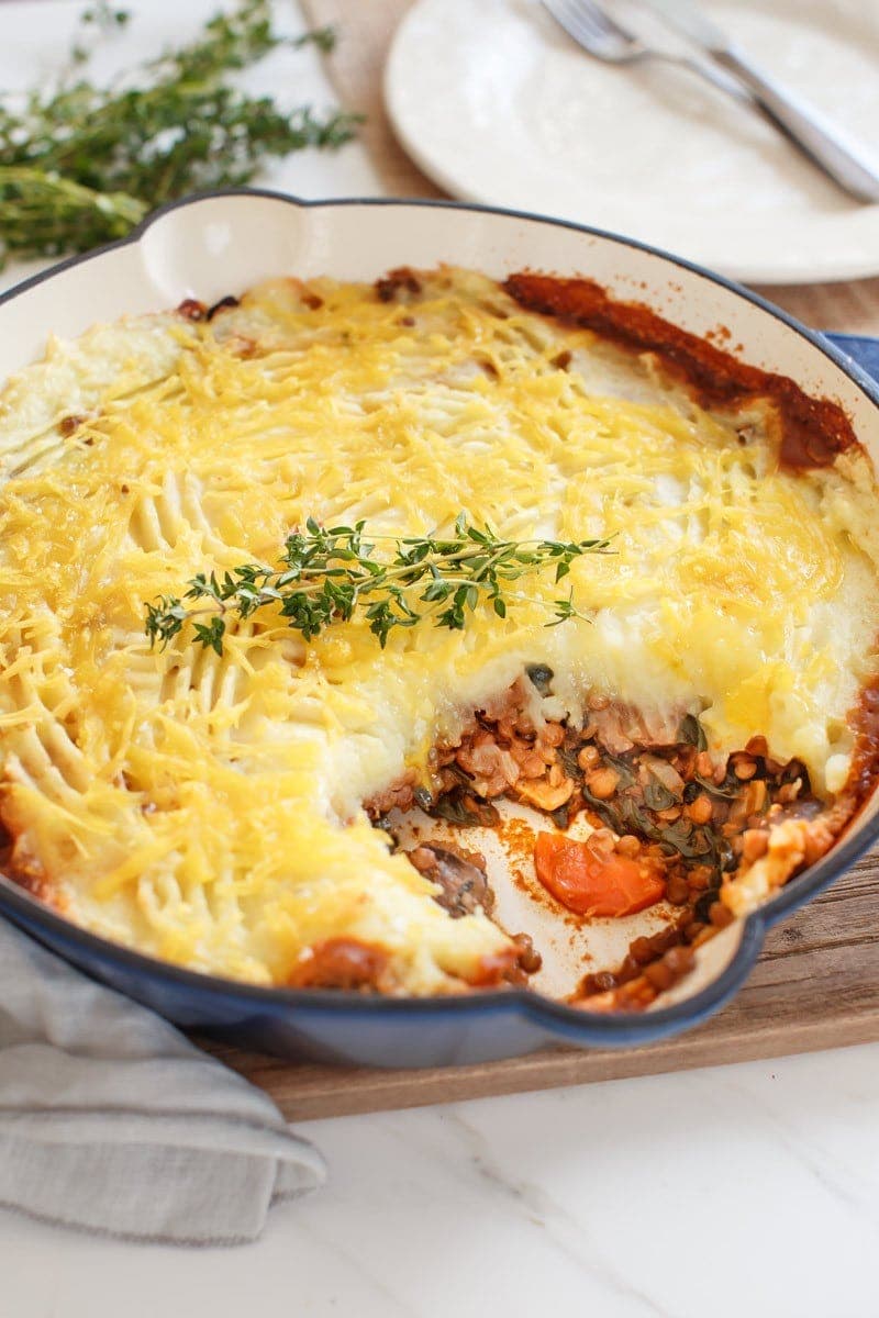 Lentil Shepherd's Pie in a skillet fresh out of the oven, with a portion served. 