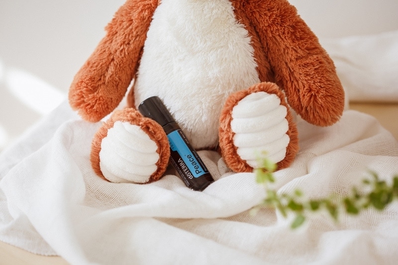 Peace essential oil nestled in beside a soft toy