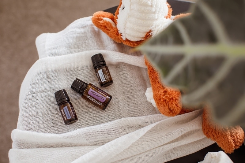 Essential oils for kids sleep on a bedside table next to soft toy