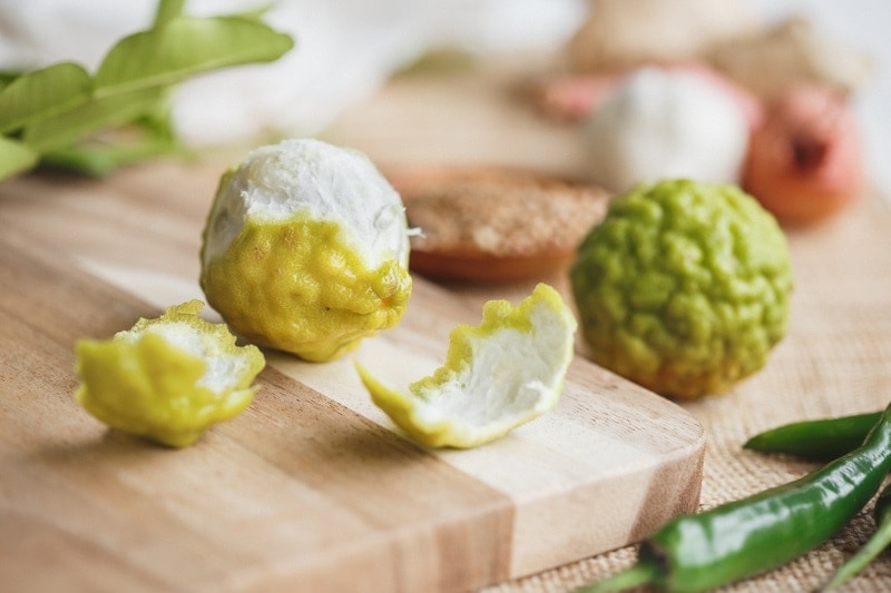 Close up of a fresh kaffir lime, half peeled, for a Thai green curry paste recipe