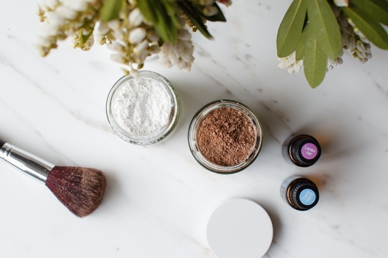 Tubs of DIY dry shampoo for light and dark hair on a marble surface