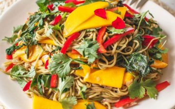 Mango Soba Noodle Salad on a woven placement with serving spoon