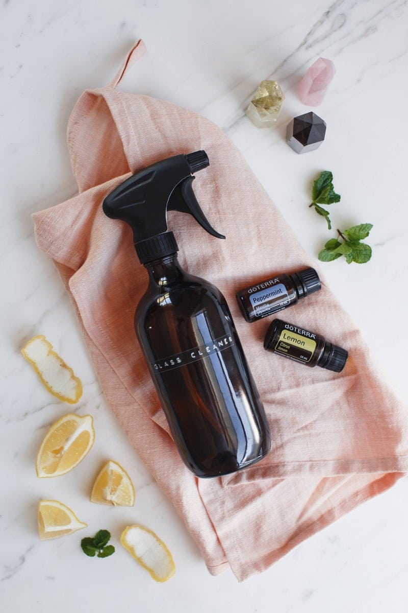 Glass spray bottle on the kitchen bench, with some fresh lemon peel and mint in the background.