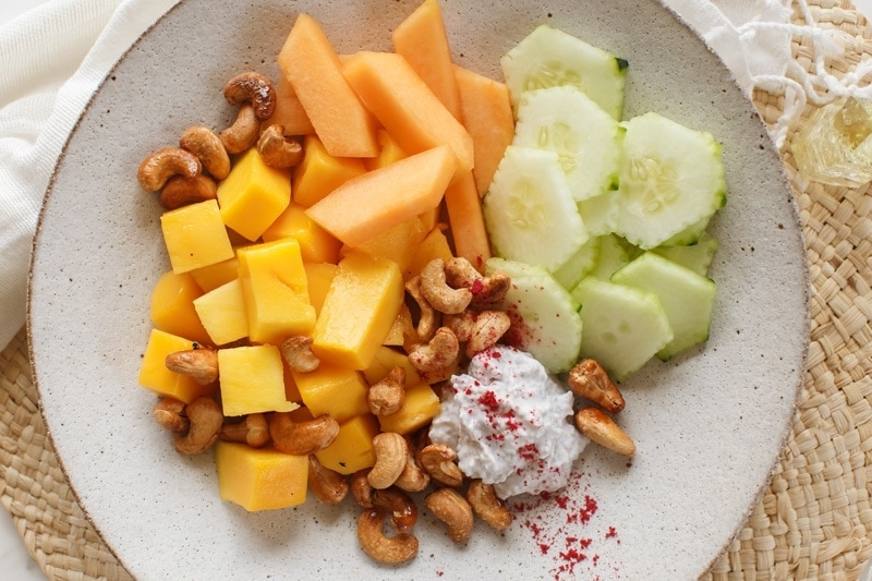 Maple roasted cashews scattered over a bowl of fresh fruit