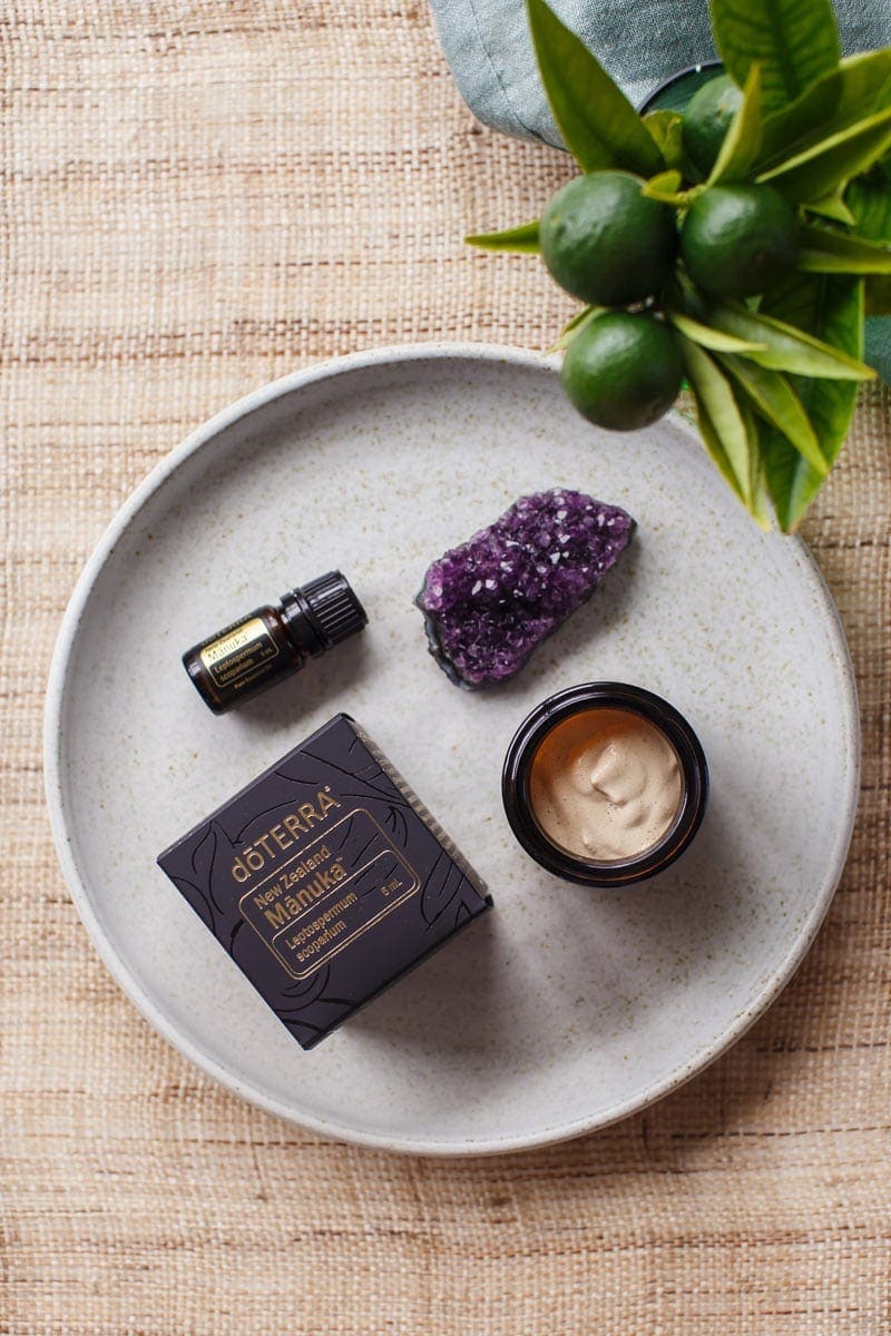 Hero shot of homemade face cream with Manuka essential oil beside it