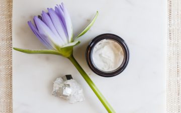 A jar of pure white skin cream styled beautifully with a flower beside it