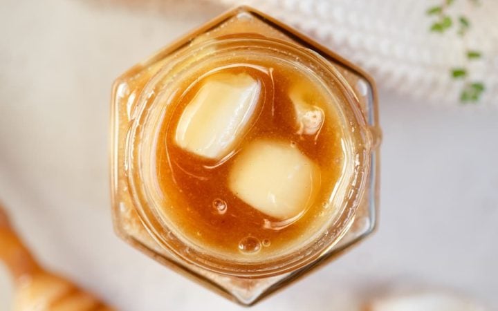 Overhead shot of a small hexagon shaped glass jar filled with fermented garlic honey