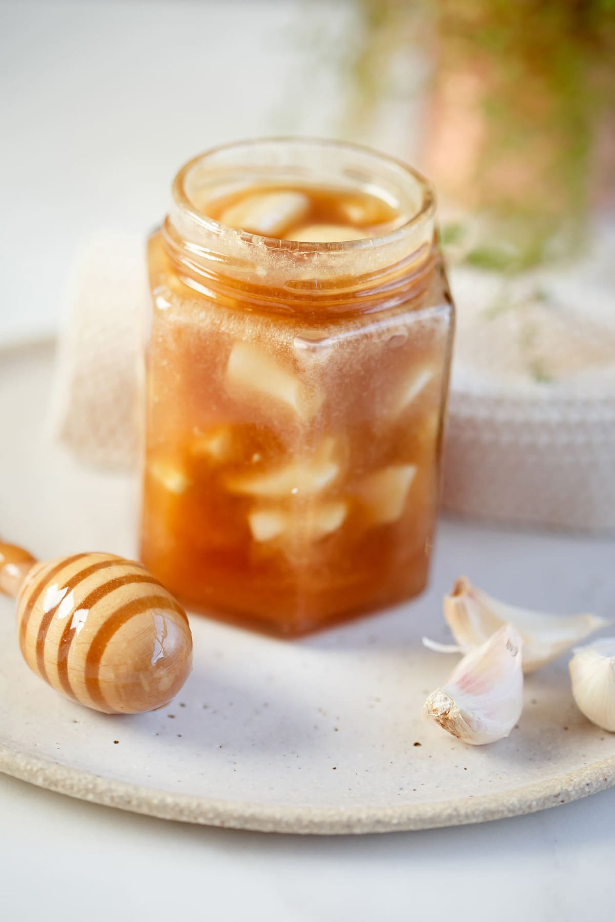 Immune Boosting Fermented Garlic Honey in a jar surrounded by garlic cloves