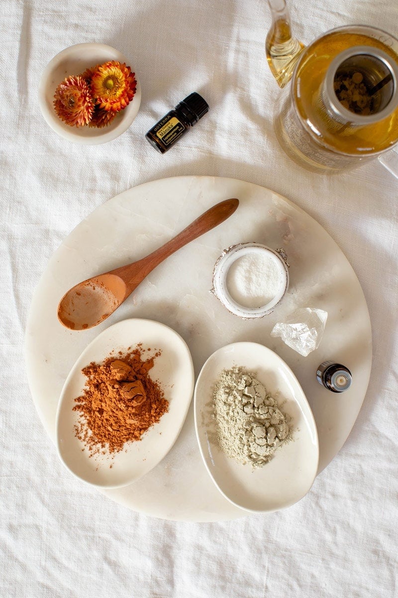 Flat lay of ingredients used to make a homemade face mask for acne, on a white marble surface.