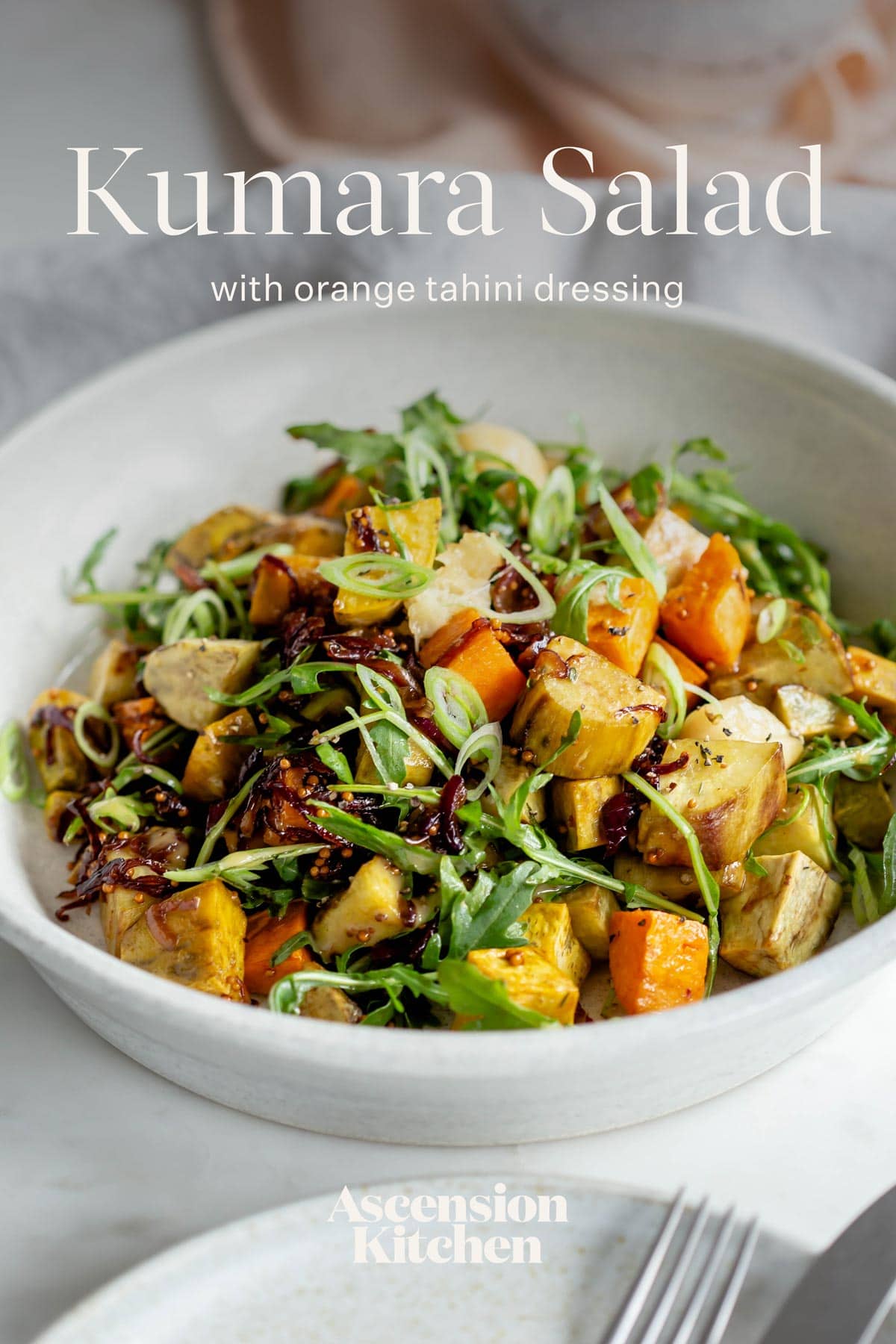 Bright and colourful roast kumara salad on a dining table. Text over the top reads "Kumara Salad with orange tahini dressing".