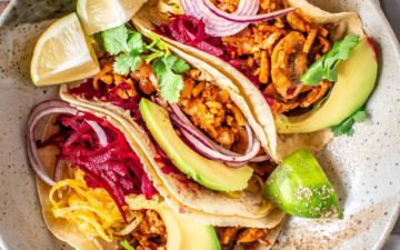 Three vibrant tempeh tacos sandwiched together