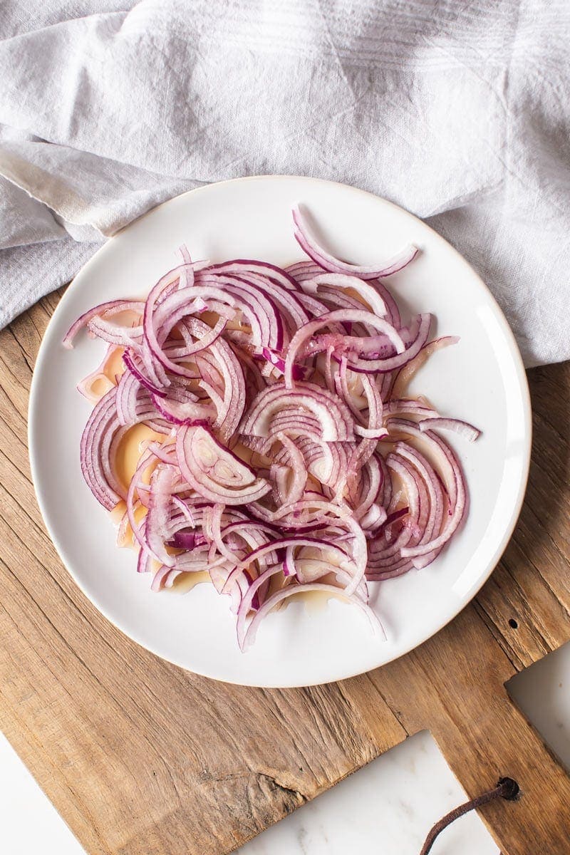 A plate filled with sliced reed onions covered with vinegar - this is how to make the quick pickles