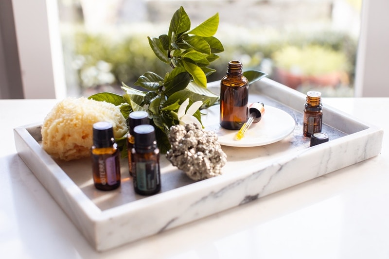 A marble tray with a beard oil, some essential oils and other men's grooming products on it