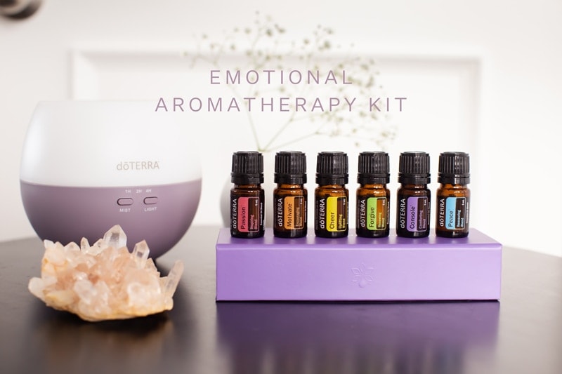 The oils in the doTERRA Emotional Aromatherapy Kit beside the Petal Diffuser, on a bedroom side table