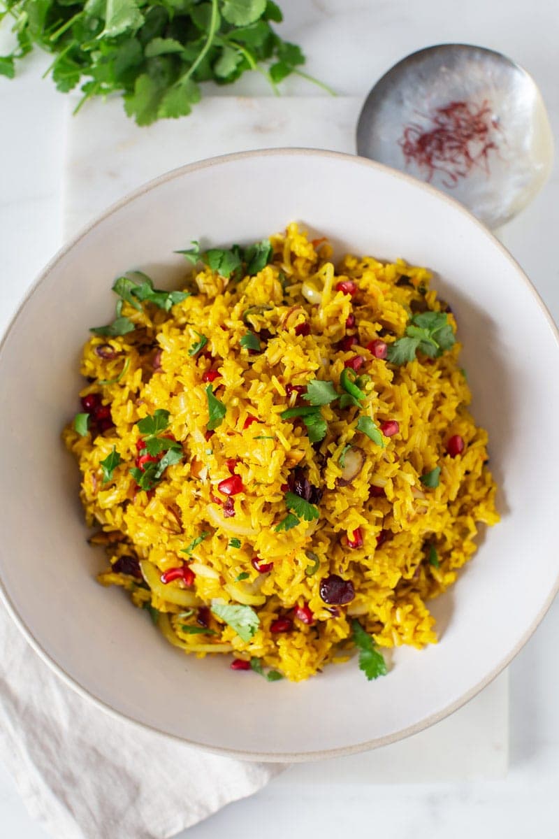 The finished saffron rice recipe, topped with fresh coriander, on a marble board