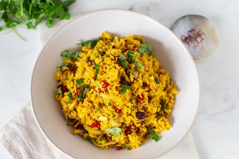 A bowl of bright yellow saffron rice on the kitchen table