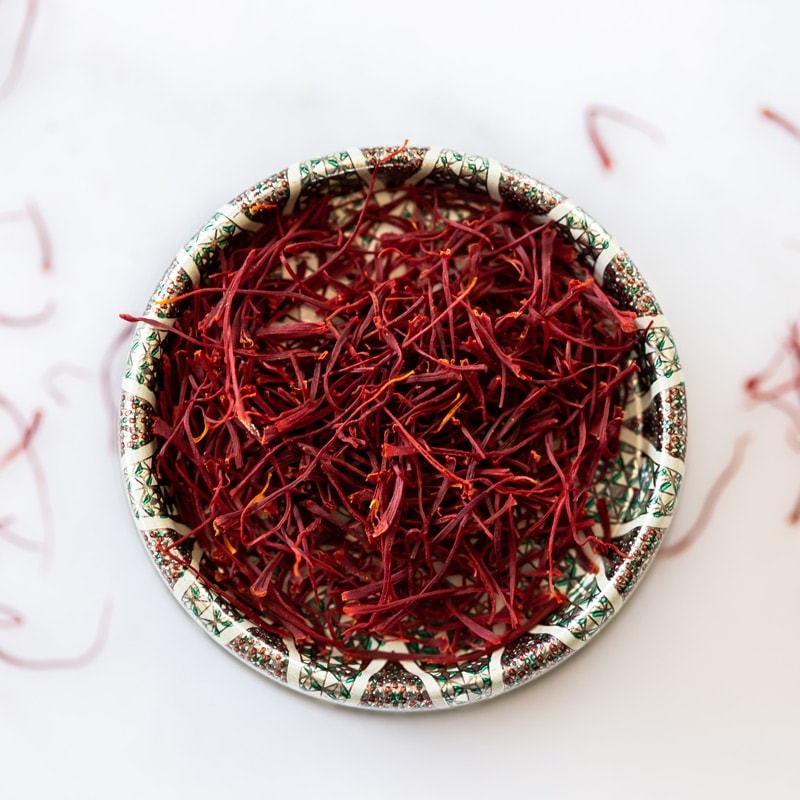 Close up of a tiny dish filled with bright red dried saffron stamens