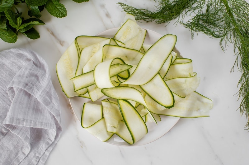 Ribbons of zucchini on a small plate having been sliced fine on a mandolin
