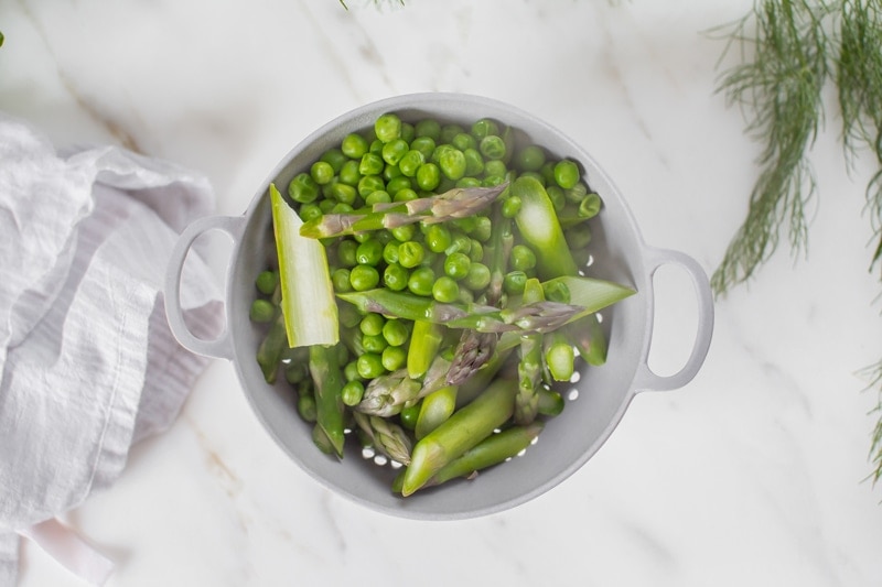 Peas and sliced asparagus in a colander after steaming