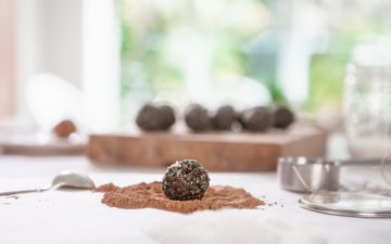 A freshly made bliss ball about to be rolled in cacao powder