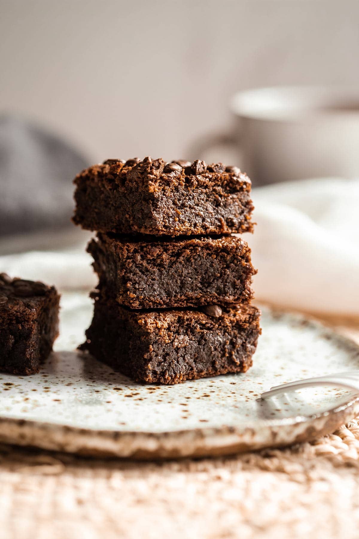 A stack of homemade brownies on a speckled plate, with super fudgy texture