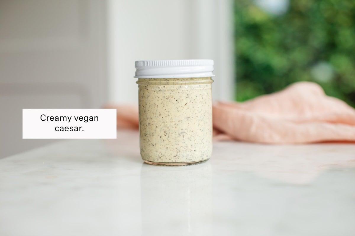 A jar of homemade vegan Caesar dressing on the kitchen bench