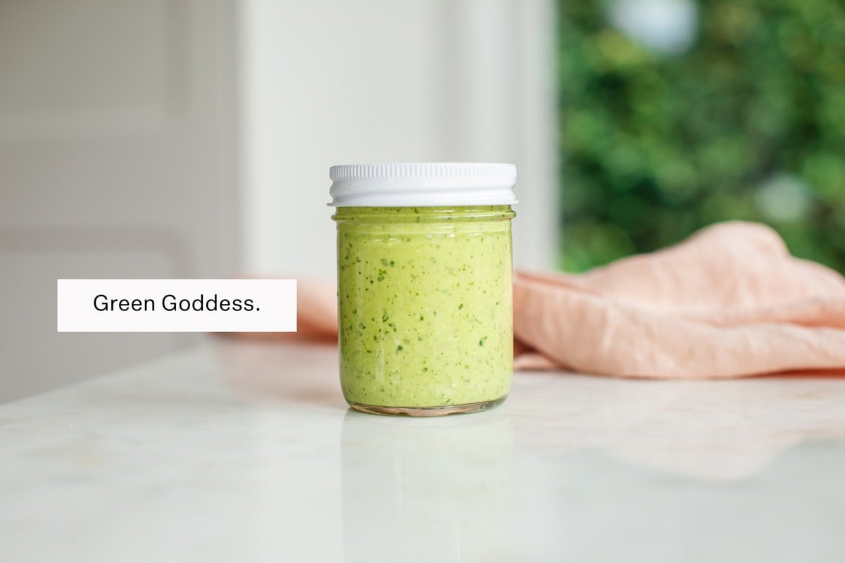 A jar of homemade green goddess dressing on the kitchen bench