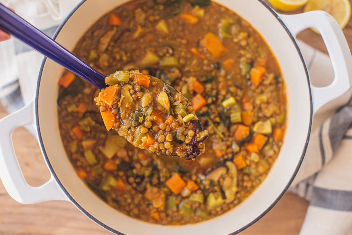 Close up of a ladle filled with chunky lentil soup