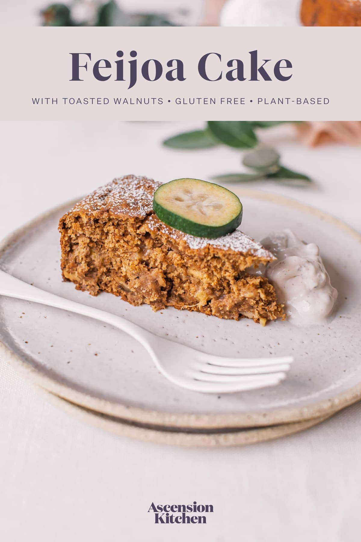 Hero shot of a slice of feijoa cake, with a dollop of coconut yoghurt on the plate next to it. Text over the top of the image reads "Feijoa Cake with toasted walnuts. Gluten free, plant-based."