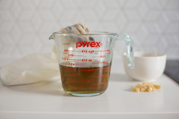 Infused oil in a pyrex jug, having been strained through muslin