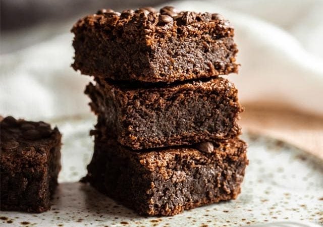 A stack of rich chickpea brownies on a speckled plate