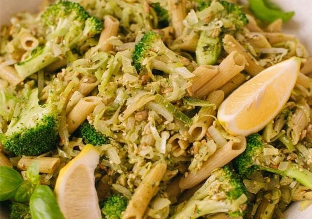 Close up of a bowl of vegan legume pasta tossed with pesto and broccoli