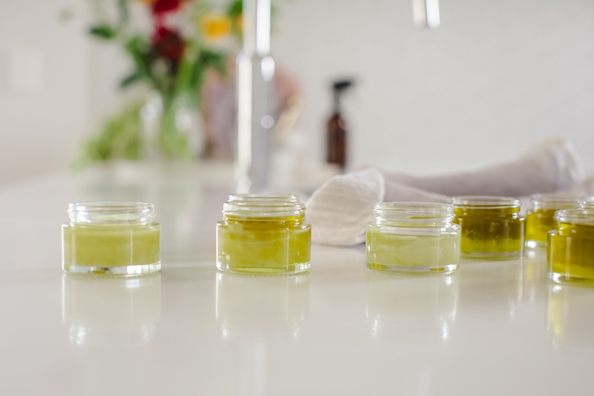 Jars of freshly poured herbal salve setting on the kitchen bench.