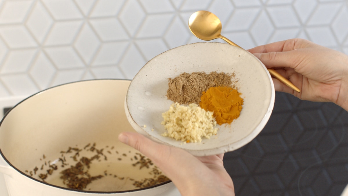 A dish filled with grated ginger, turmeric powder and ground coriander, about to add to the pot