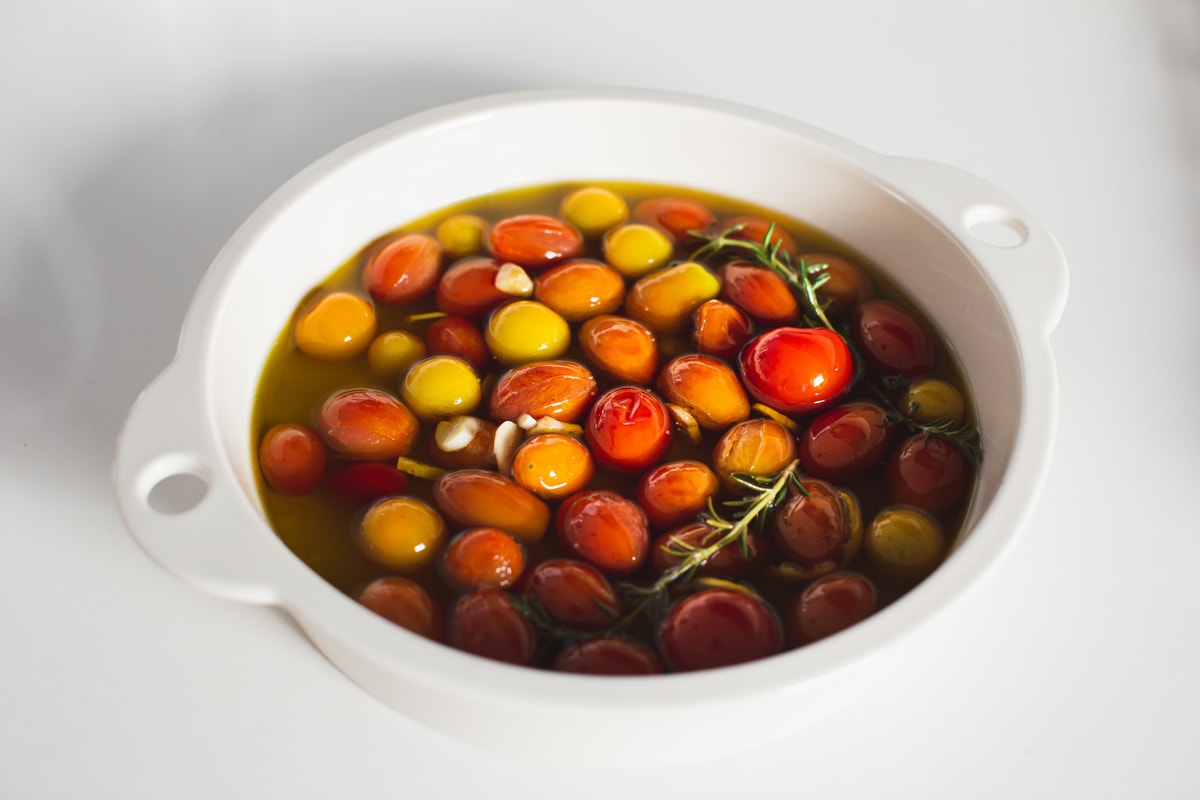 White baking dish with a single layer of tomatoes, covered in oil oil - it is now ready to go in the oven for several hours