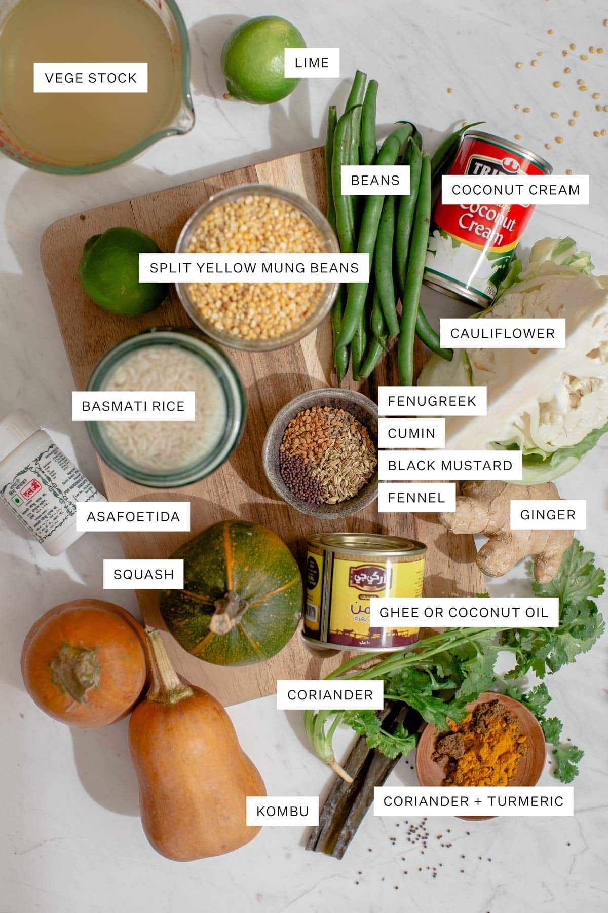 Flat lay of ingredients needed for this dish, including the dal and rice, dried spices, vegetables, ghee, coconut cream, stock, fresh herbs and lime.