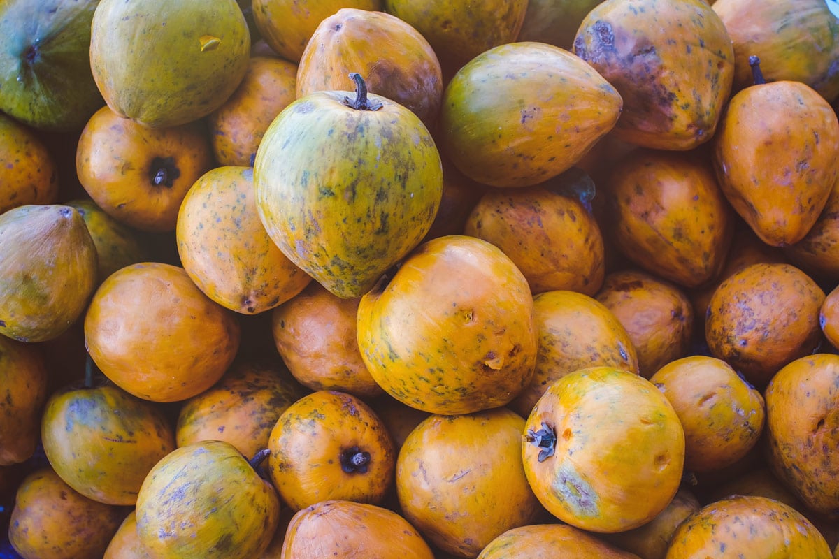 Close up of a market stall packed with fresh, ripe lucuma fruit.