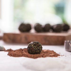 A bliss ball on the kitchen counter about to be rolled in cacao powder.