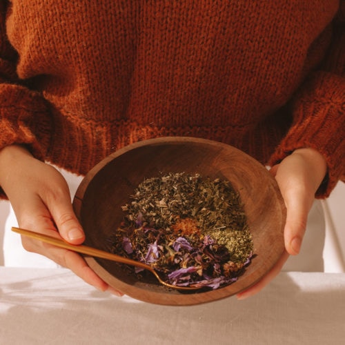 Lauren holding a bowl full of herbs used to make a herbal dream tea blend.